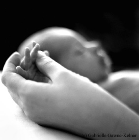 Image of baby holding its mother's hand, illustrating an article on postnatal depression and therapy